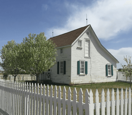 The Donelson House today: white clapboard with green shutters behind a picket fence and flowering trees