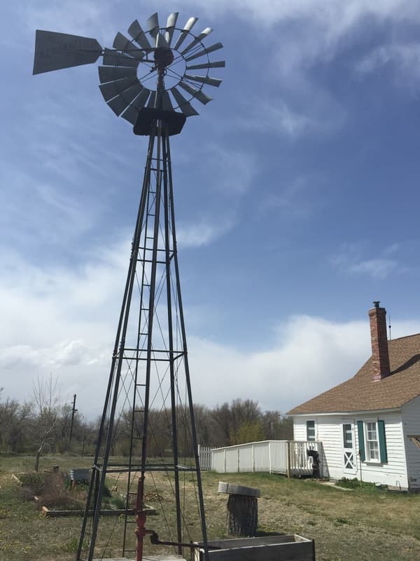 A tall windmill against a deep blue sky beside the Donelson House