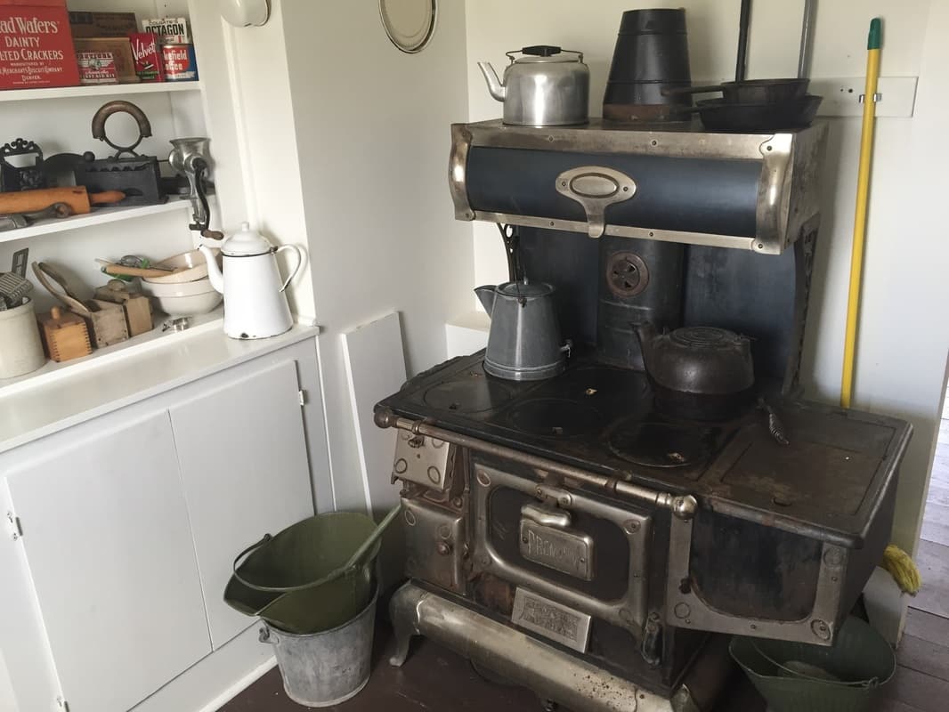 The kitchen's nickel-trimmed cast-iron cook stove with kettles and shelves of vintage tins