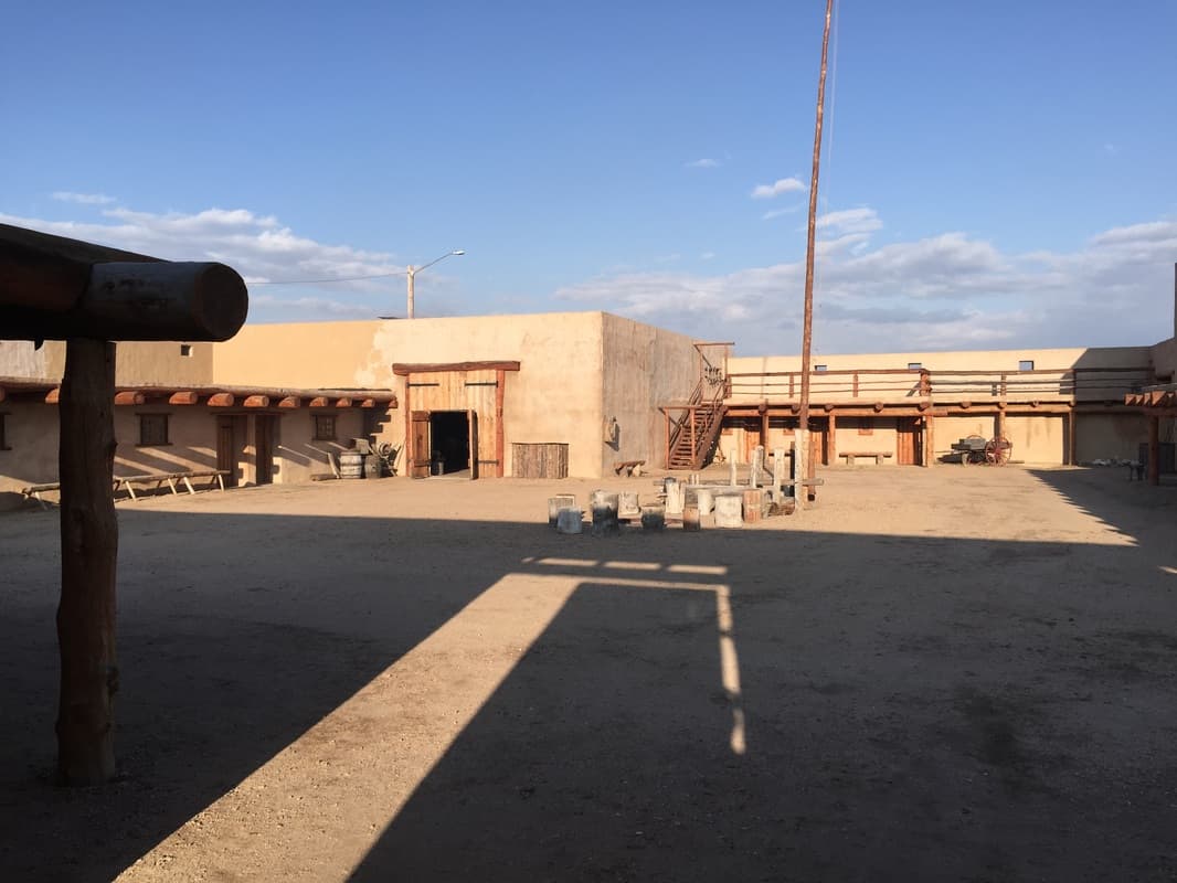 The courtyard looking toward the balcony and stairs, with the flagpole, a wagon and rows of stumps