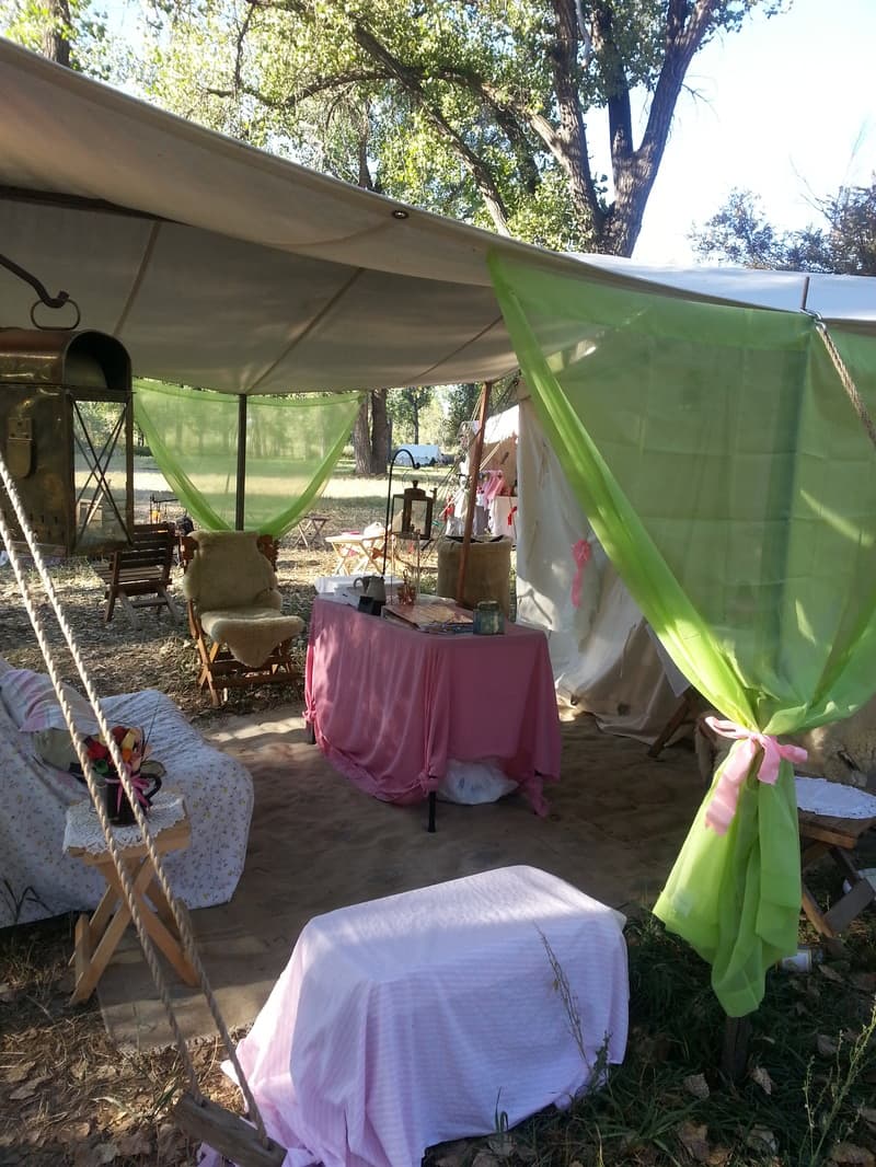 Inside the Hunter's Widows tent: a pink-draped table, a sheepskin chair, green sheers and a camp lantern