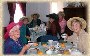 Ladies in hats at a tea table set with teacups and pumpkins