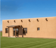 Rendering of the planned adobe-style visitor center and restrooms on a lawn under a blue sky